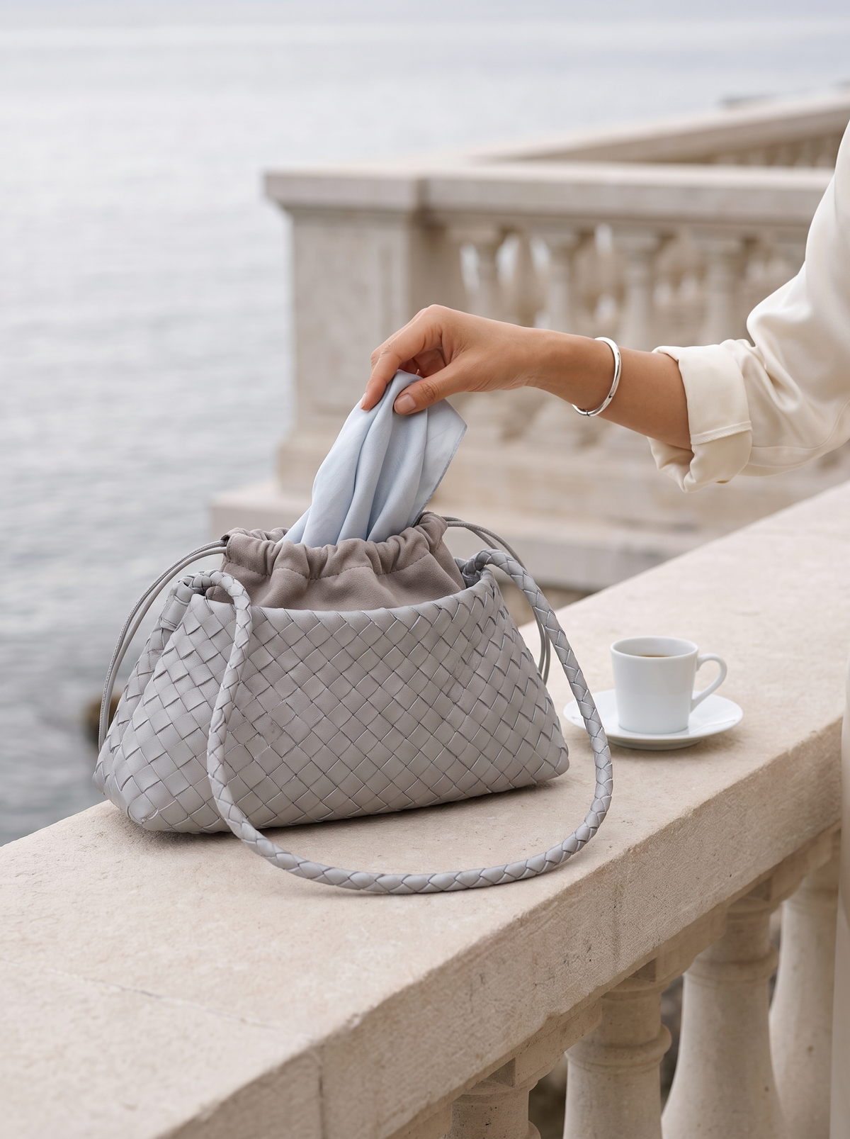 The Antibes in Dove on a terrace balustrade, a silk scarf drawn from the pouch