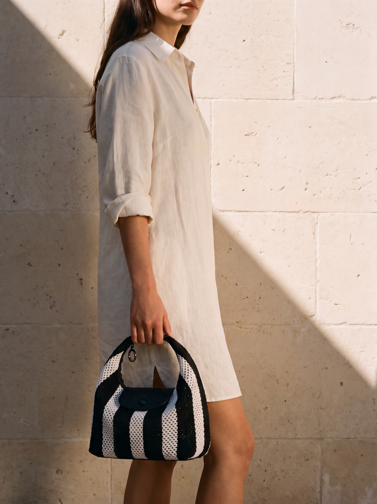 The Deauville in Stripe Noir, held in hand by a limestone wall