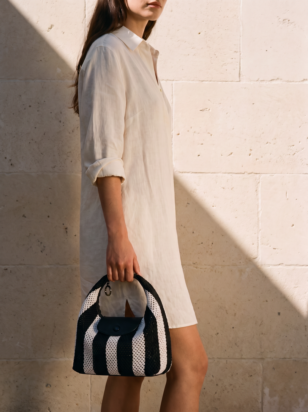 The Deauville in Stripe Noir, held in hand by a limestone wall