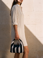 The Deauville in Stripe Noir, held in hand by a limestone wall